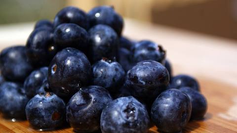 A pile of fresh blueberries on a wooden board