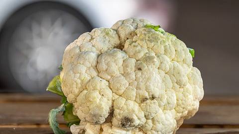 A whole cauliflower on a wooden surface