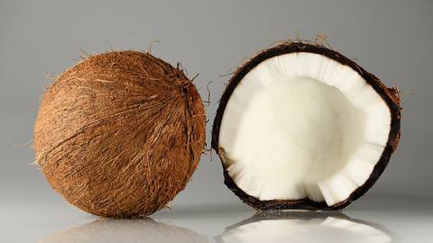 A whole coconut next to a halved coconut