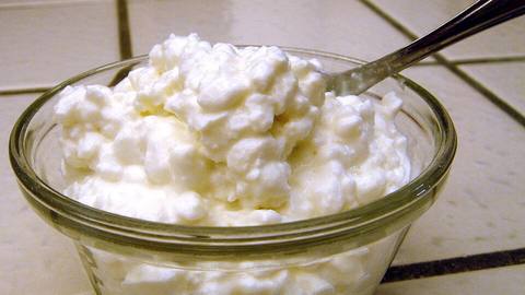 A glass bowl of cottage cheese with a spoon