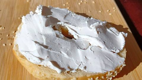 Cream cheese spread on a sesame bagel half