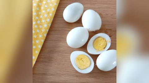 Peeled hard-boiled eggs, some halved to show the yolk