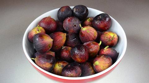 A white bowl of fresh dark figs