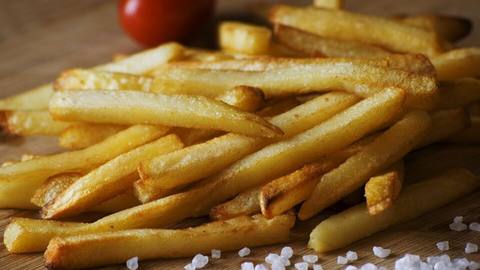 A pile of golden french fries with a sprinkle of salt
