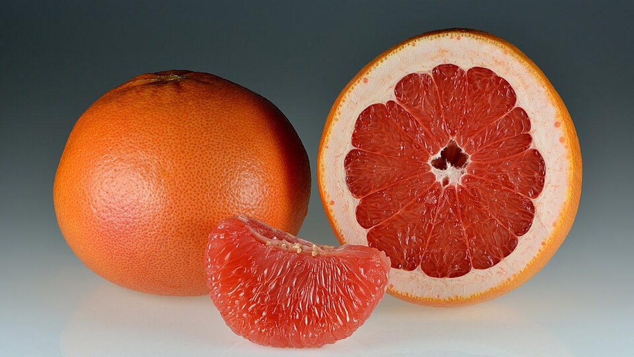 A whole grapefruit beside a halved one and a segment