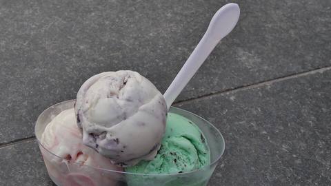 Scoops of ice cream in a plastic tub with a spoon