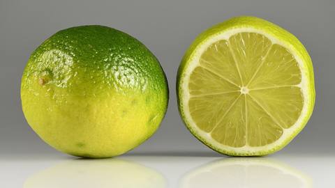 A whole lime next to a halved lime