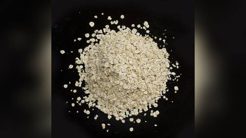 A small heap of rolled oats on a black background