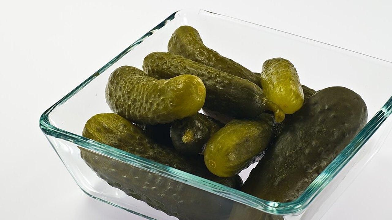 A glass dish of small pickled gherkins