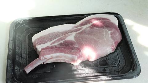 A raw pork chop on a black tray