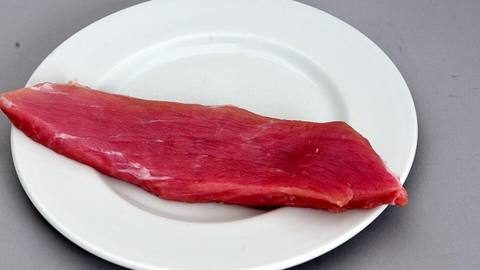 A strip of raw red meat on a white plate
