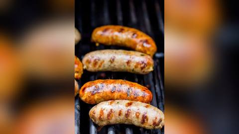 Raw sausages cooking on a barbecue grill