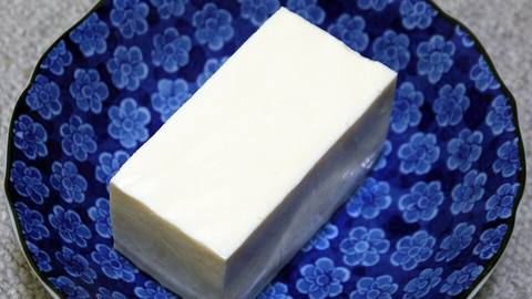 A block of white tofu on a blue patterned plate