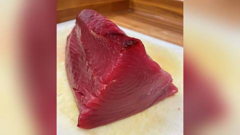 A cut section of raw tuna on a blue surface
