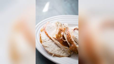 Plain cooked boneless turkey breast, sliced and unseasoned, on a light ceramic plate