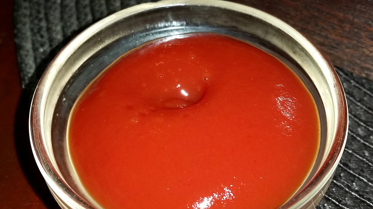 A glass bowl of ketchup
