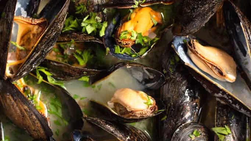 Cooked mussels in a pot with herbs and broth